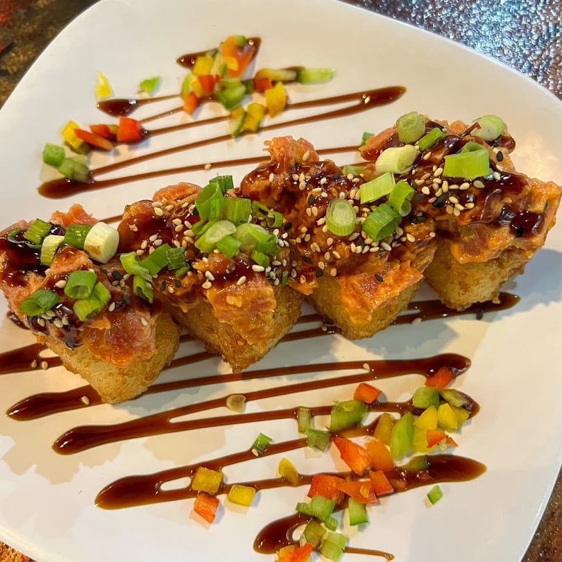 Four pieces of spicy tuna crispy rice with scallions, sesame seeds, and balsamic glaze.