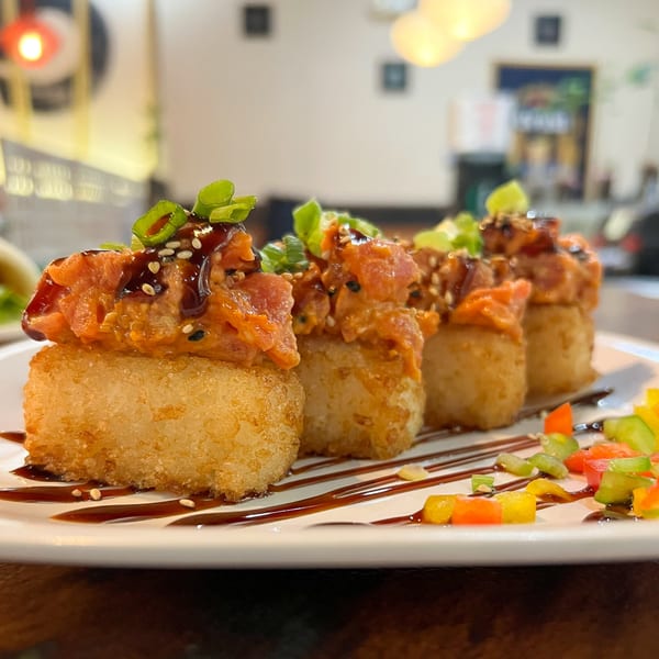 Four pieces of crispy rice topped with spicy tuna, green onions, and sesame seeds.